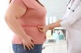 Female,doctor,measuring,waist,of,overweight,woman,with,measuring,tape